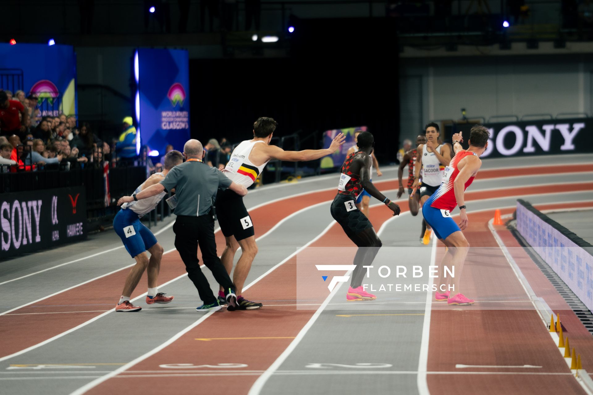 Ein Wettkampfrichter sortiert in letzter Sekunde die Reihenfolge die Aufstellung der Wechsel nochmal um. Jonathan Sacoor (BEL/Belgium), Christian Iguacel (BEL/Belgium) am 03.03.2024 bei den World Athletics Indoor Championships in Glasgow (Schottland / Vereinigtes Königreich)